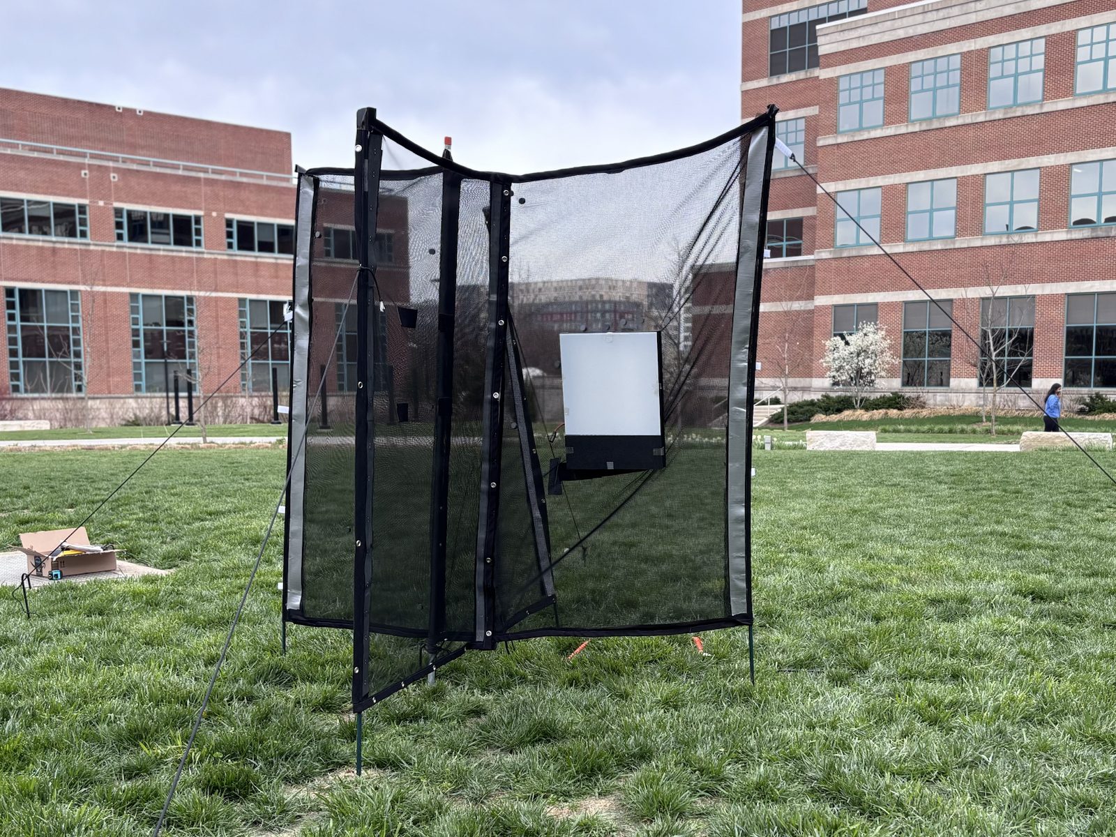 Malaise-style insect trap deployed on a lawn, with mesh wings funnelling insects toward a backlit imaging panel