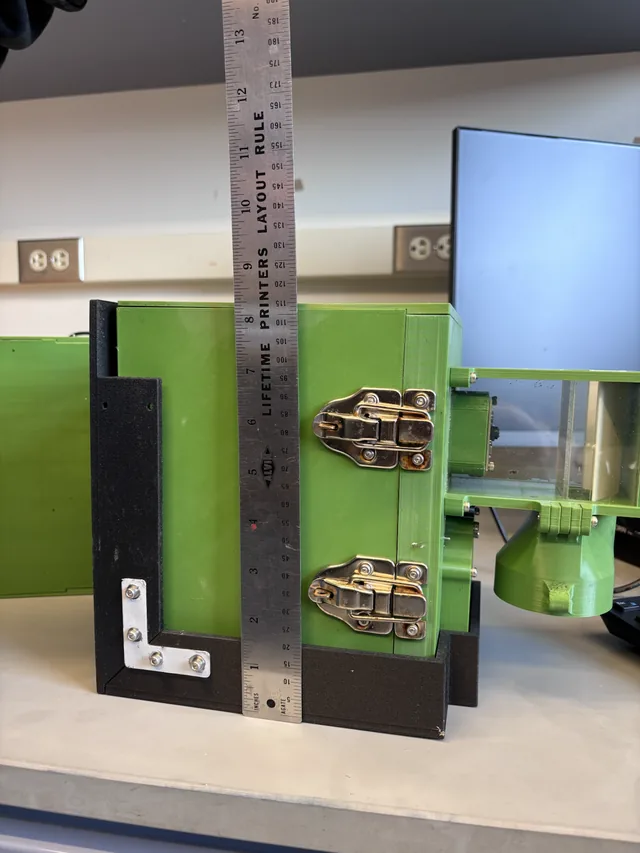 Assembled printed enclosure with latches and hinges, measured against a machinist's rule